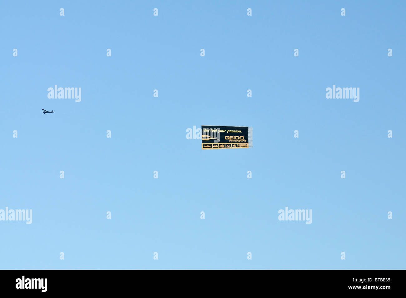 Small airplane towing an advertising banner for GEICO Powersports Stock