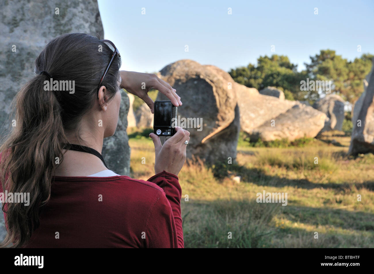 A tourist takes a photograph of the standing stones at Carnac Stock Photo