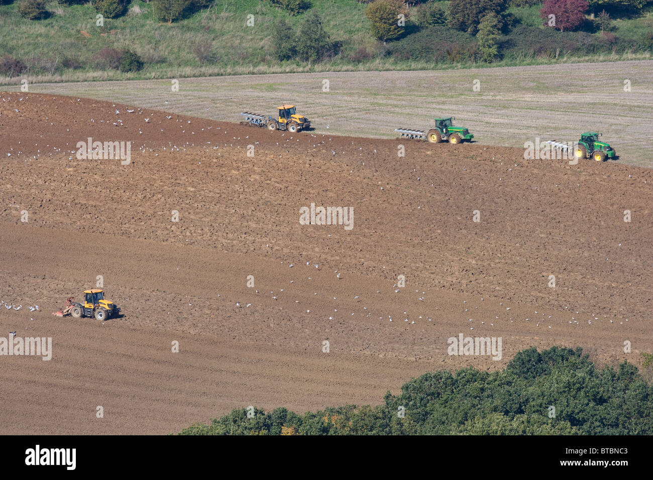 Tractors ploughing and working land down ready for drilling in the rolling Leicestershire countryside Stock Photo