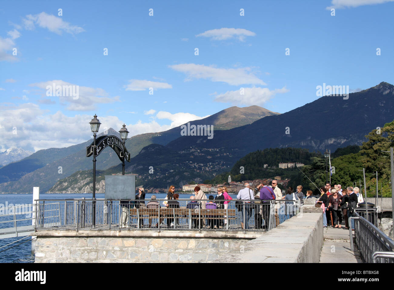 tourists at ferry pier at San Giovanni, Lake Como, Lombardy, Italy - Bellagio in the background Stock Photo