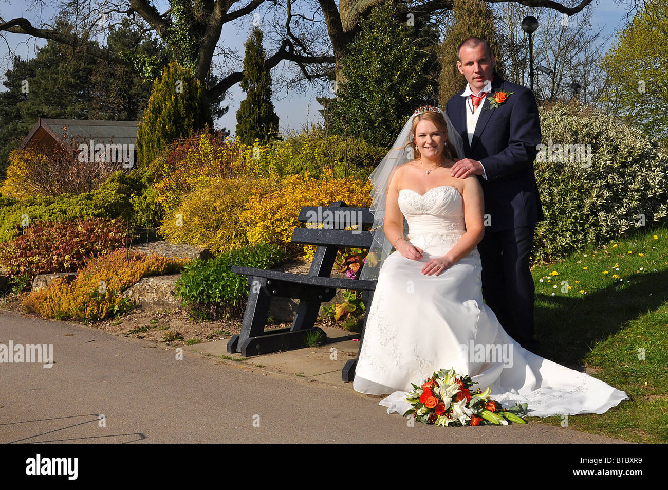 groom standing behind bride sitting on a bench Stock Photo - Alamy