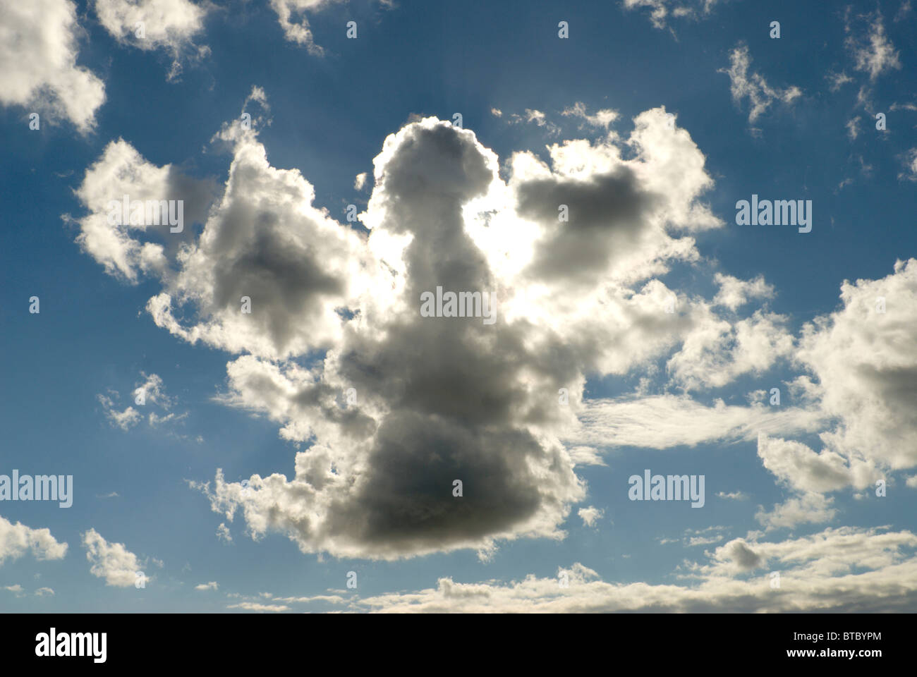 Cloud formation in the shape of an Angel or a map of the UK with sunlight behind Stock Photo