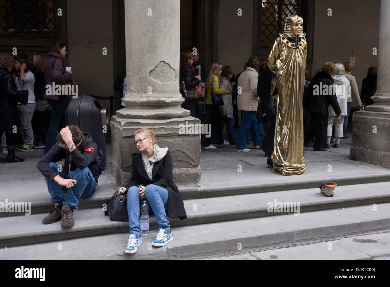 Tired and disappointed tourists and Egyptian pharaoh busker in Florence's Piazza degli Uffizi Stock Photo