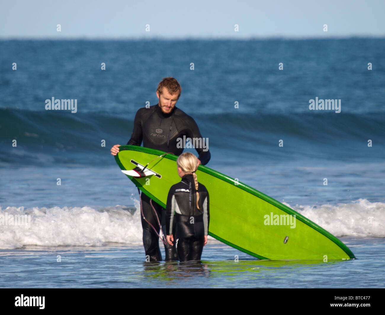 Father giving a surfing lesson to daughter, Bude, Cornwall, UK Stock Photo