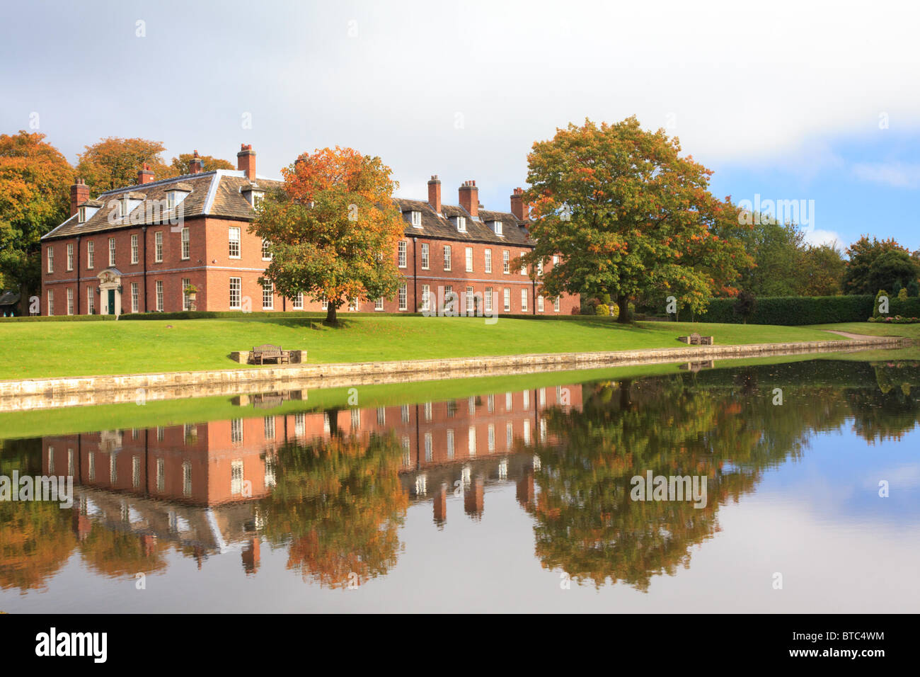 Gawsworth new hall in cheshire a grade II listed country house viewed across the lake in autumn. Stock Photo