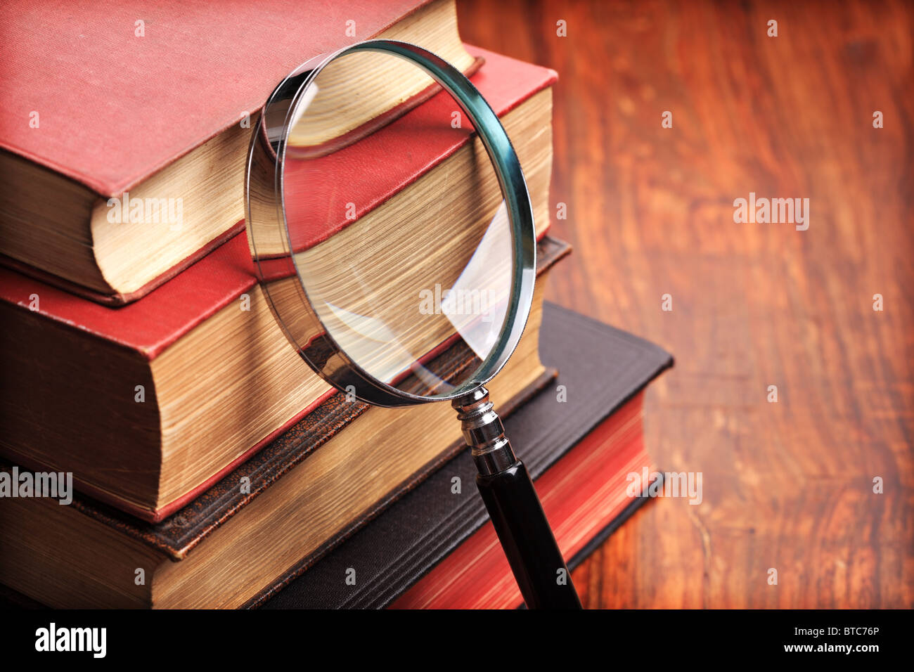 Magnifying glass with old books Stock Photo