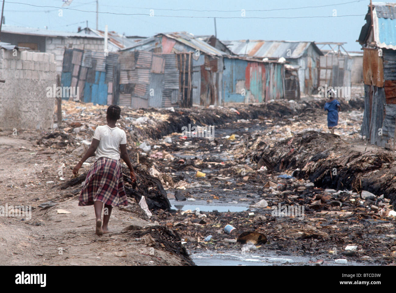 haiti-girl-walking-by-open-sewage-in-the-slums-of-of-cite-soleil-port-BTCD3W.jpg