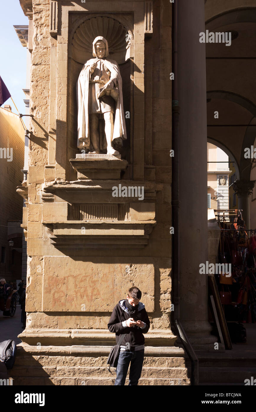 Renaissance statue figure looks down on disaffected youth in Florence's Piazza di Mercato Nueva Stock Photo