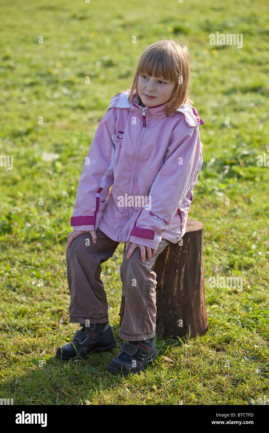 portrait of a small girl sitting on a tree stump Stock Photo - Alamy