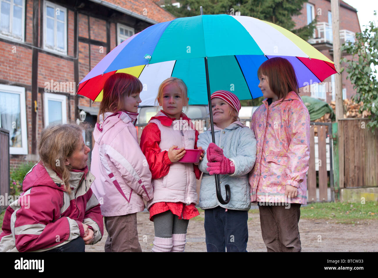 portrait of four small girls under a colourful umbrella Stock Photo