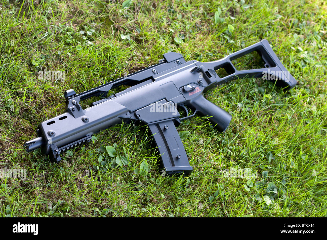 Black automatic rifle lying in the grass. Stock Photo