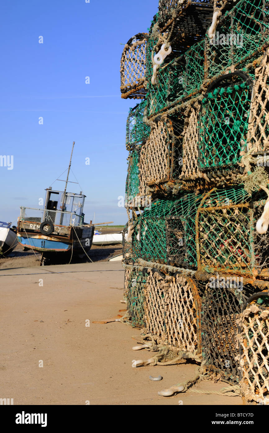 A moored fishing boat framed by Lobster Pots at Brancaster Staithe Stock Photo