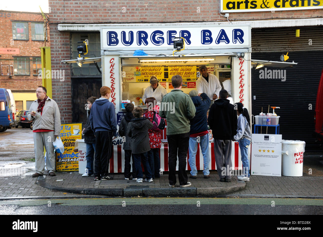 People, including children buying burgers from Burger Bar stall in Benwell Road on Arsenal match day Holloway Stock Photo
