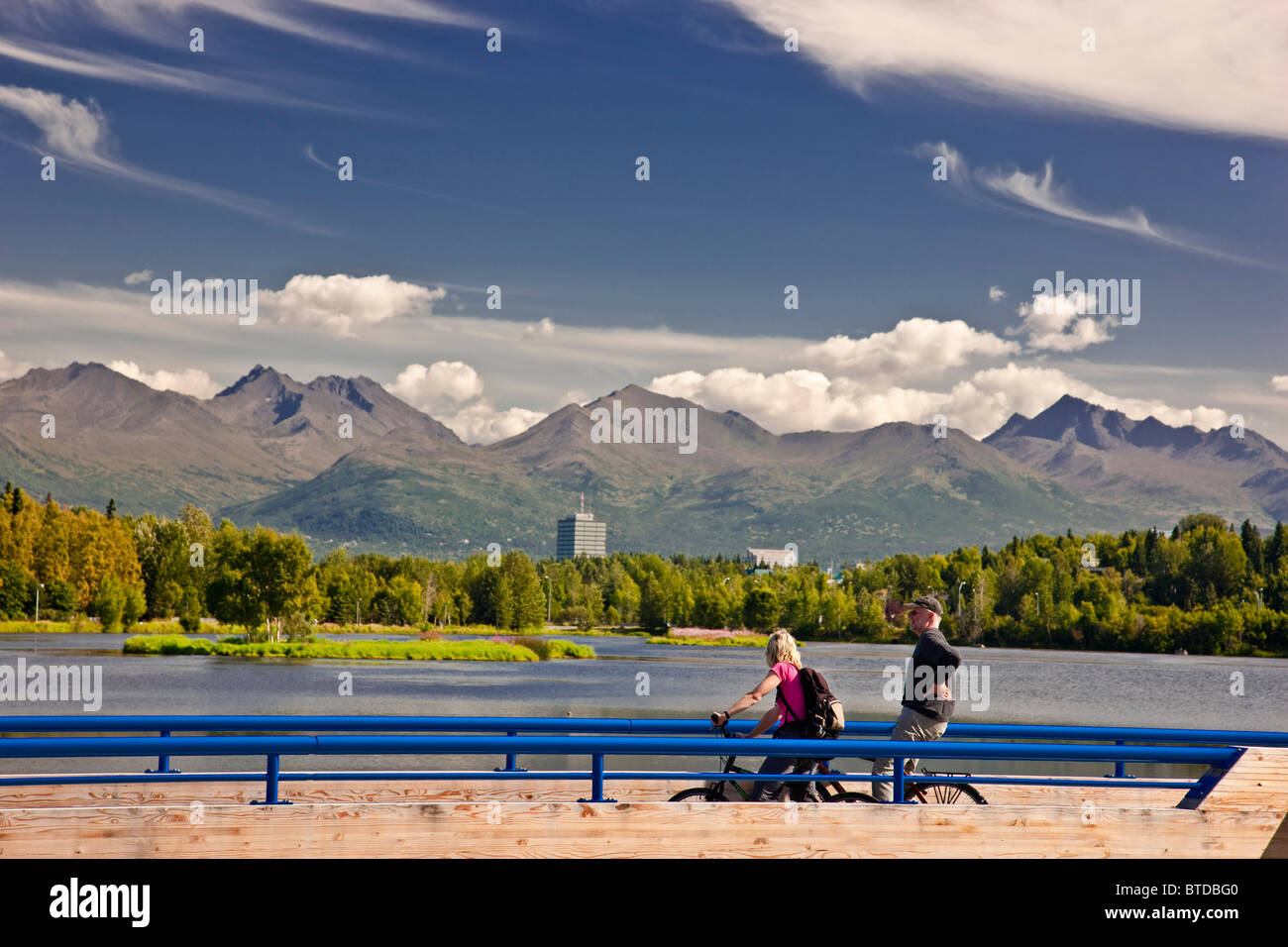 Bikers overlooking Westchester Lagoon from the Tony Knowles Coastal Trail during Summer, Anchorage Southcentral Alaska Stock Photo