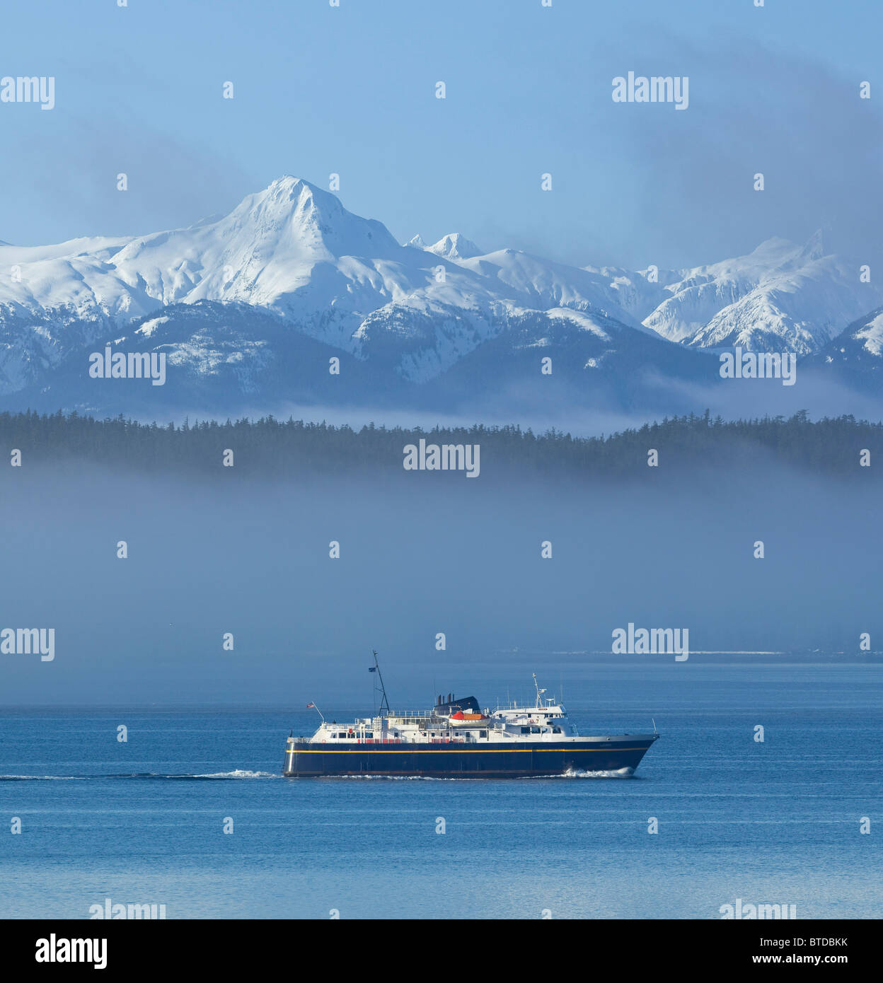 Alaska Marine Highway Ferry cruises through the mist, Inside Passage with snowcovered peaks in the background, Alaska COMPOSITE Stock Photo