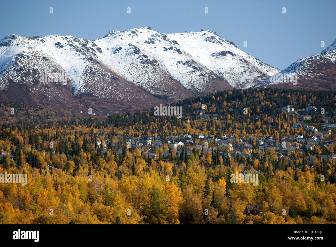 Scenic view of Anchorage's residential hillside with snowcapped Chugach Mountains in the background during Autumn, Alaska Stock Photo