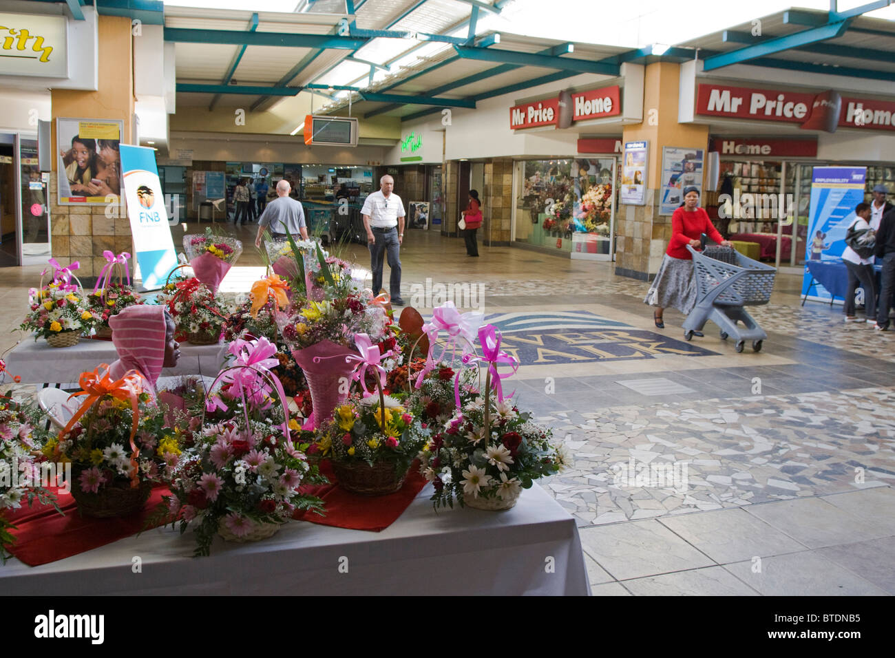 Shoppers in the Riverwalk Shopping Mall with bouquets of flowers on display in the foreground Stock Photo