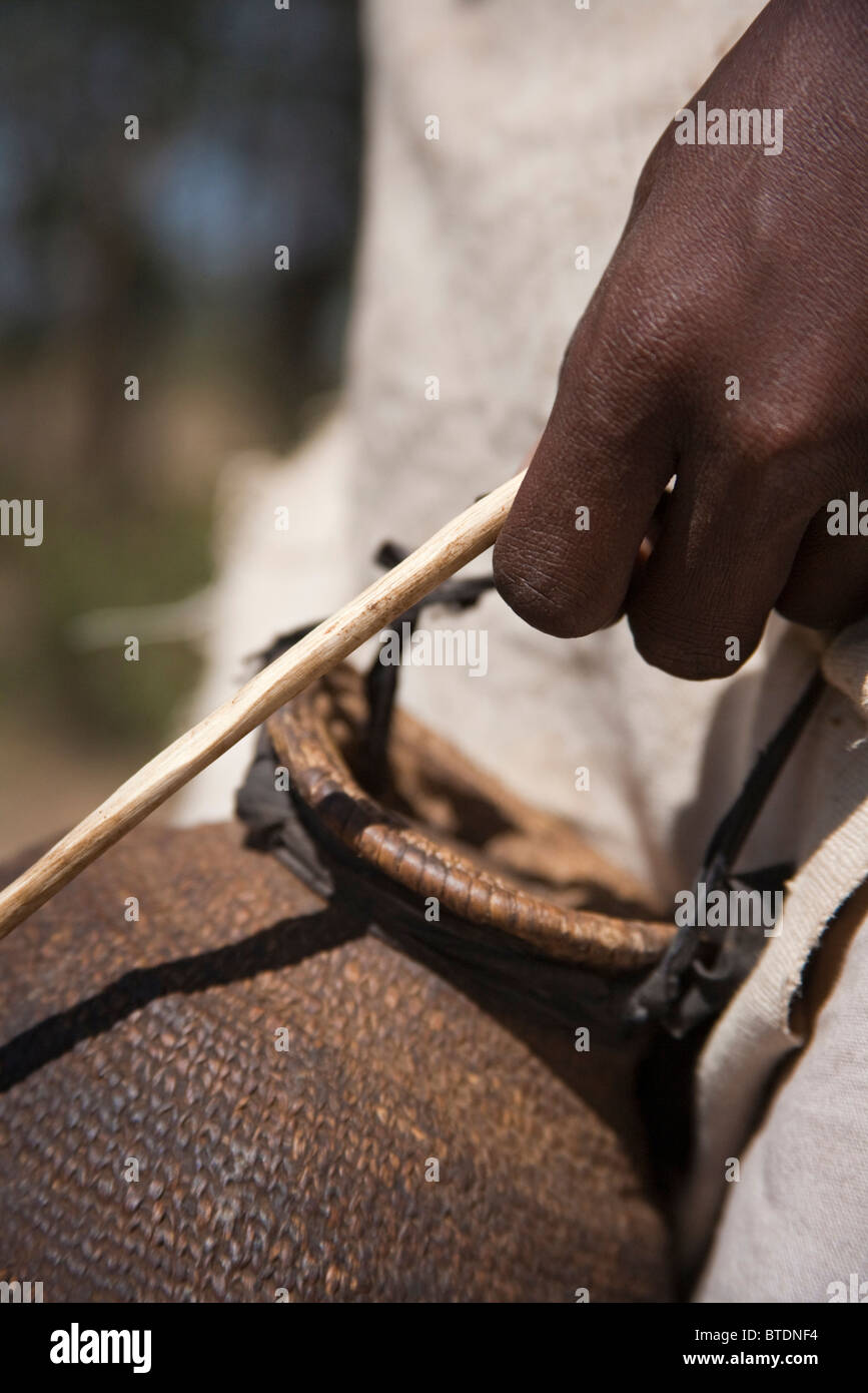 Close up of a tightly woven container used to carry milk and the hand of a camel herder Stock Photo