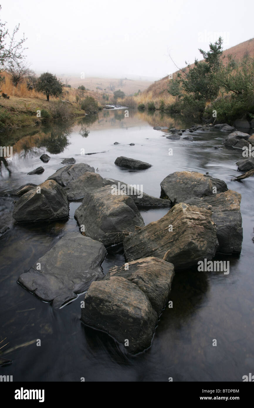 A highveld stream flowing with large rocks in the foreground Stock Photo