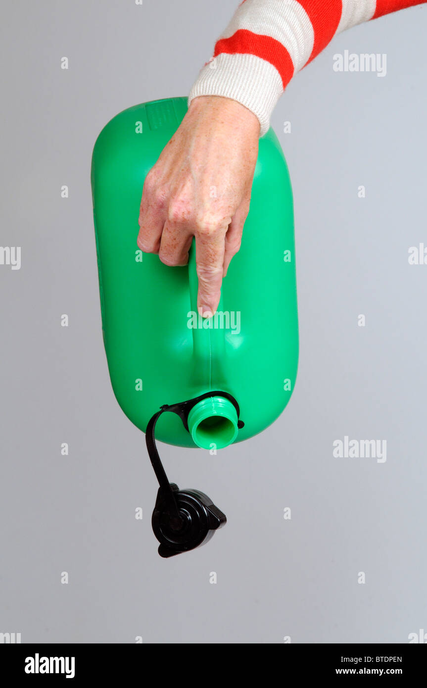 Woman holding an empty green coloured plastic petrol can Stock Photo