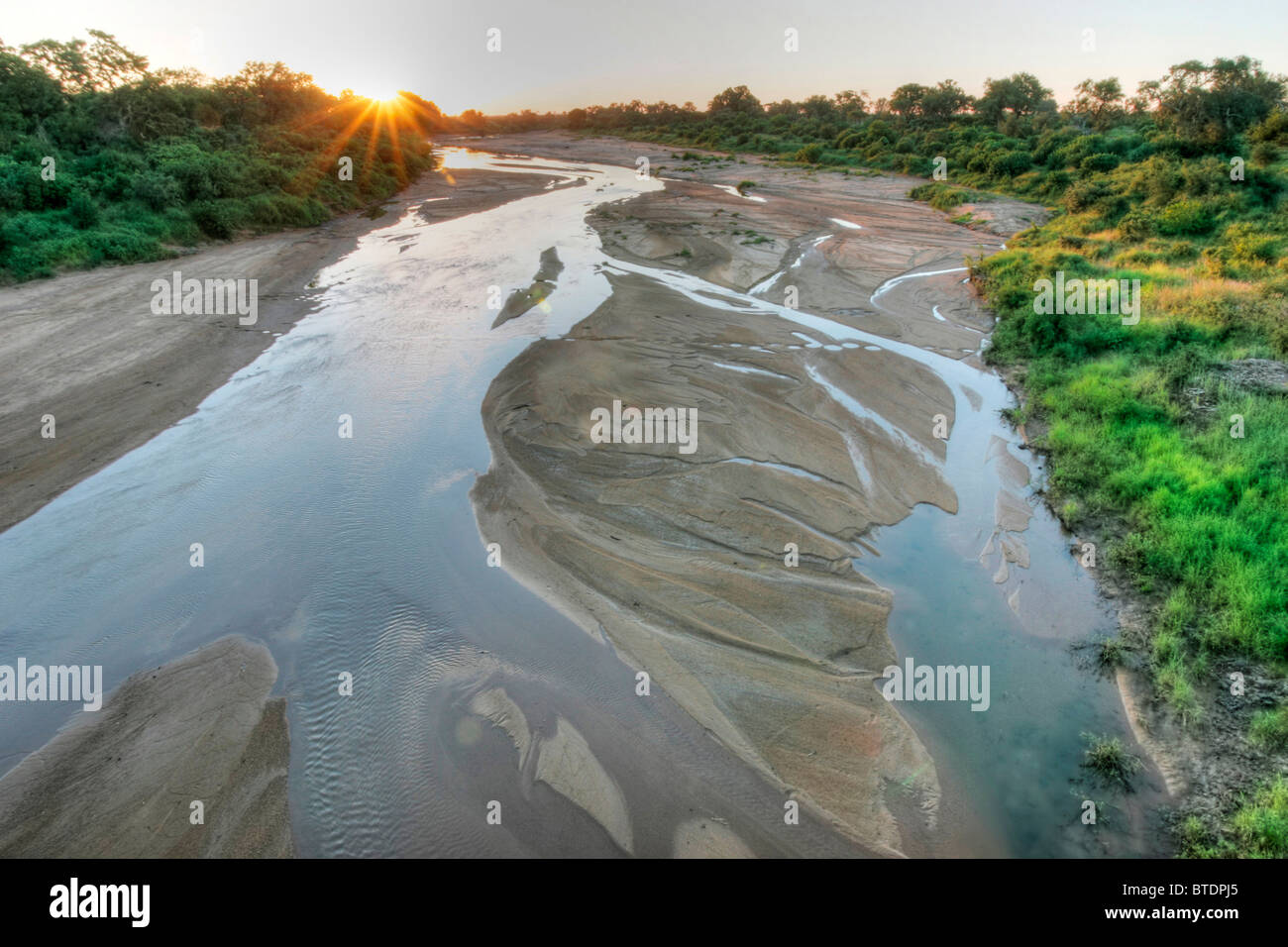 A river bed with seasonal water flowing around sand banks Stock Photo