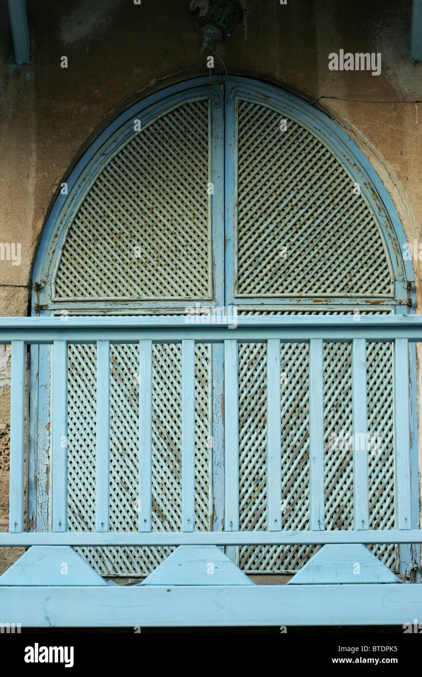 A blue arched window shutter and a blue railing in the foreground Stock Photo