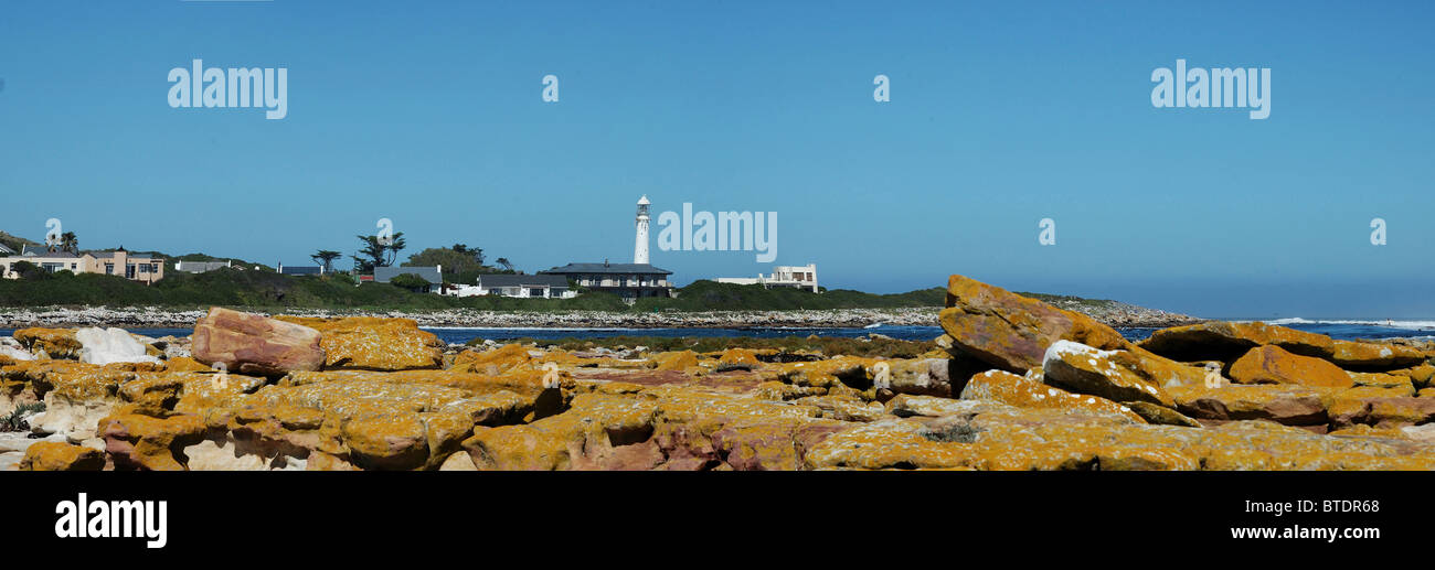 A panoramic view of a rocky seashore with a lighthouse in the background Stock Photo