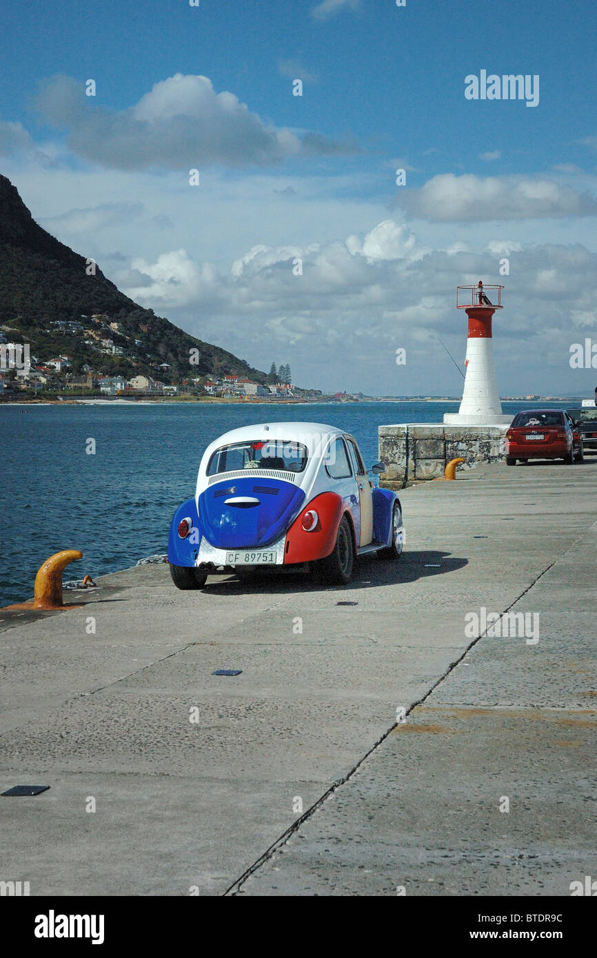 Lighthouse and a blue, red and white VW Beetle parked along the quay Stock Photo