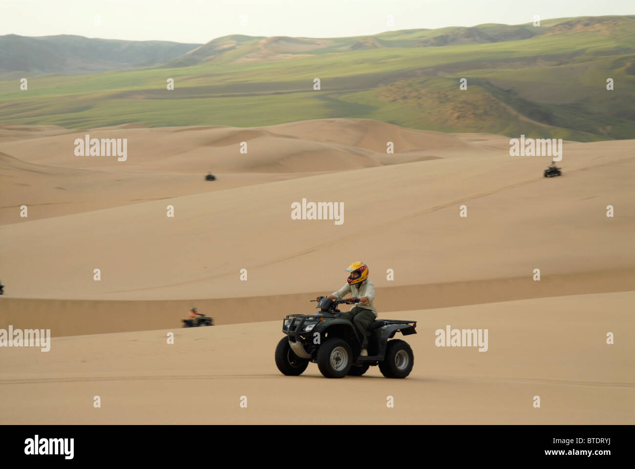 Scenic view of tourists on quad bikes on dune fields Stock Photo