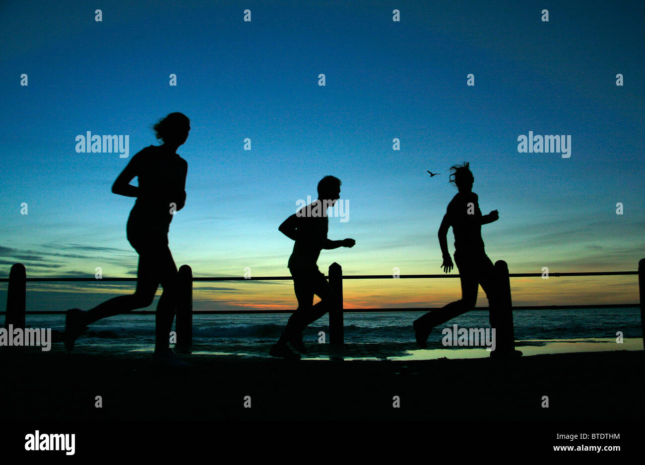 People jogging at sunset along Sea Point Stock Photo