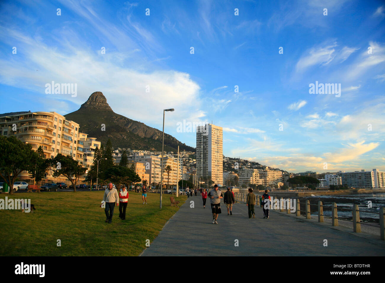 Walkers and joggers with Lions Head in back at Sea Point beachfront Stock Photo