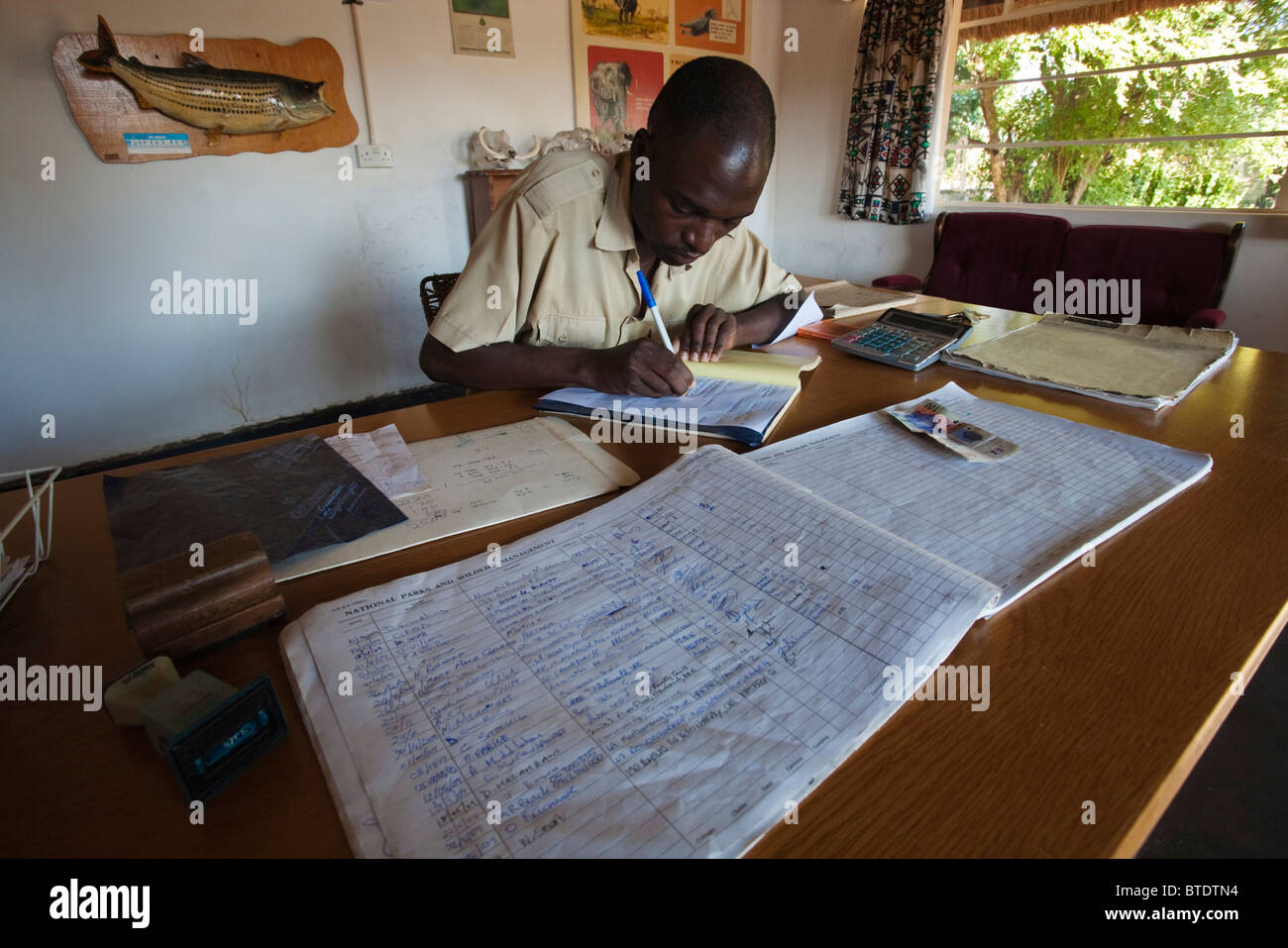 A tourism reception officer signs new guests to the reserve into the visitors book Stock Photo
