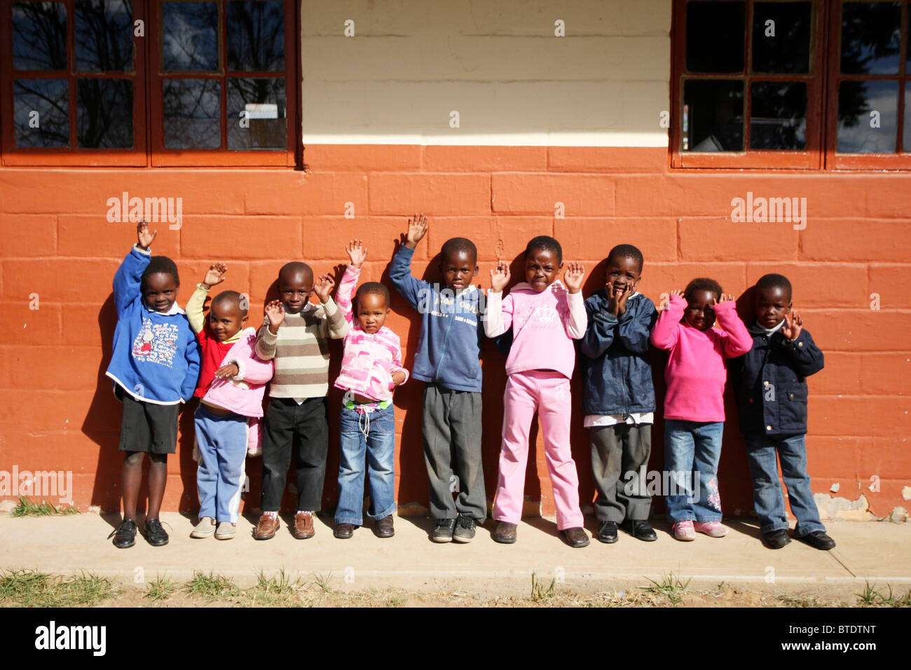 Pre school children standing outside a classroom waving in a rural Kwazulu Natal school Stock Photo