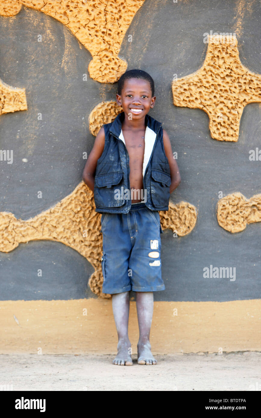 Young boy leaning against a kraal wall with traditional patterns on it Stock Photo
