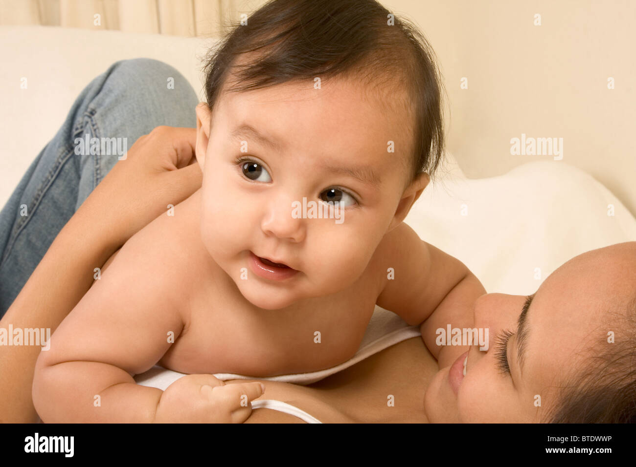 Mom lying down on bed and infant baby lies on her stomach Stock Photo