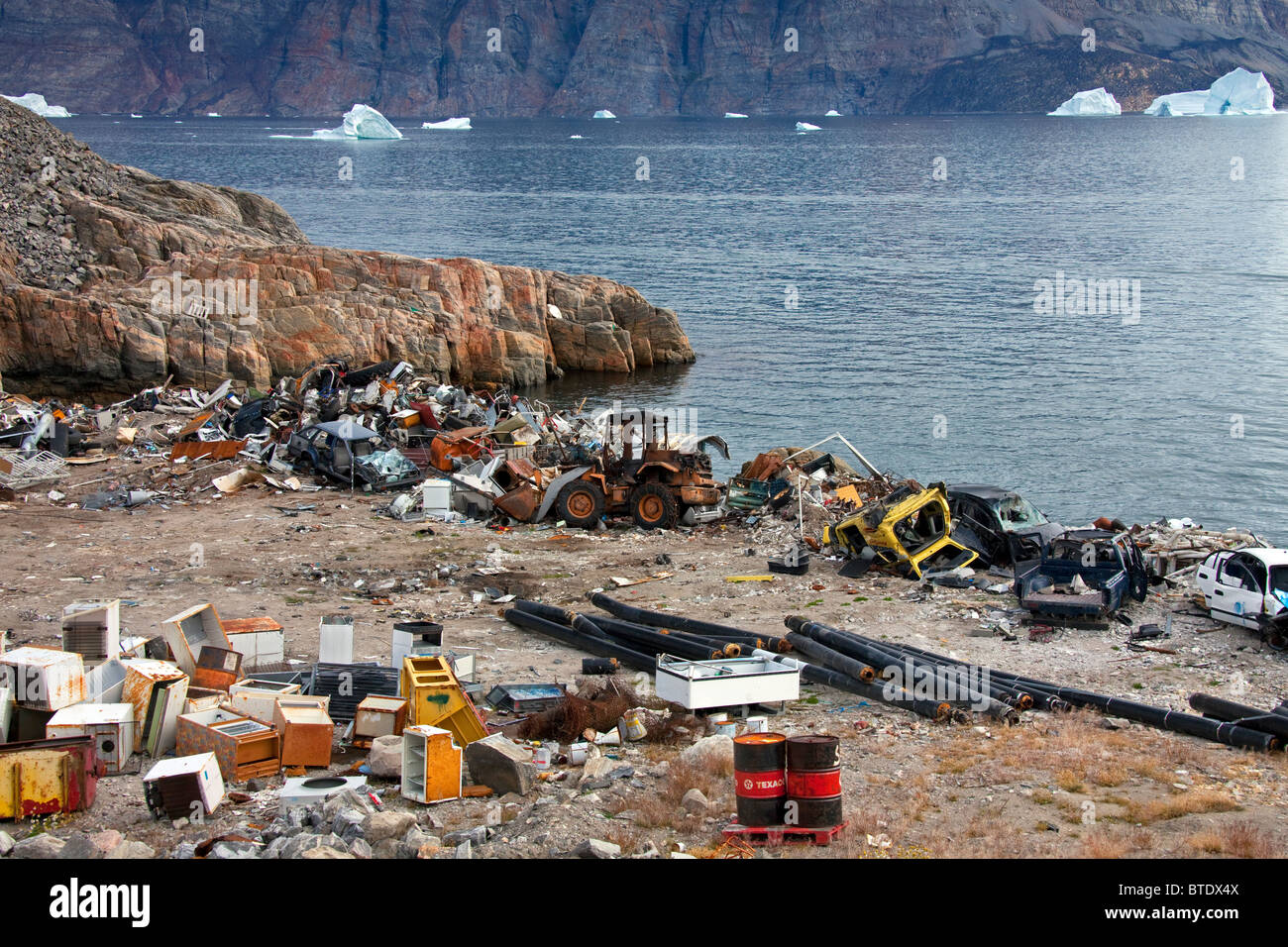 Rubbish at garbage dump and icebergs at the fishing village Uummannaq, Greenland Stock Photo