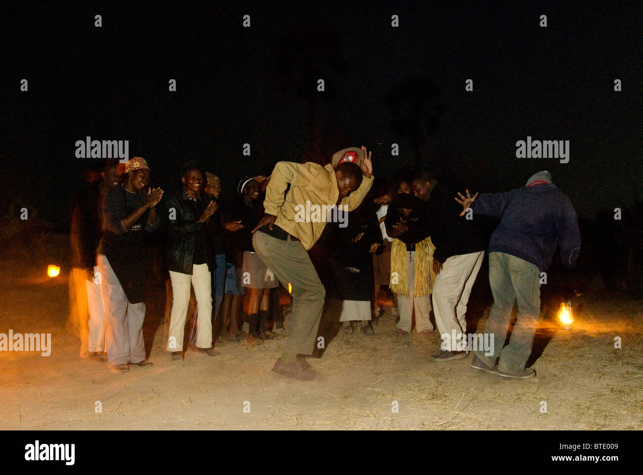 Local people dancing around a small campfire at night Stock Photo