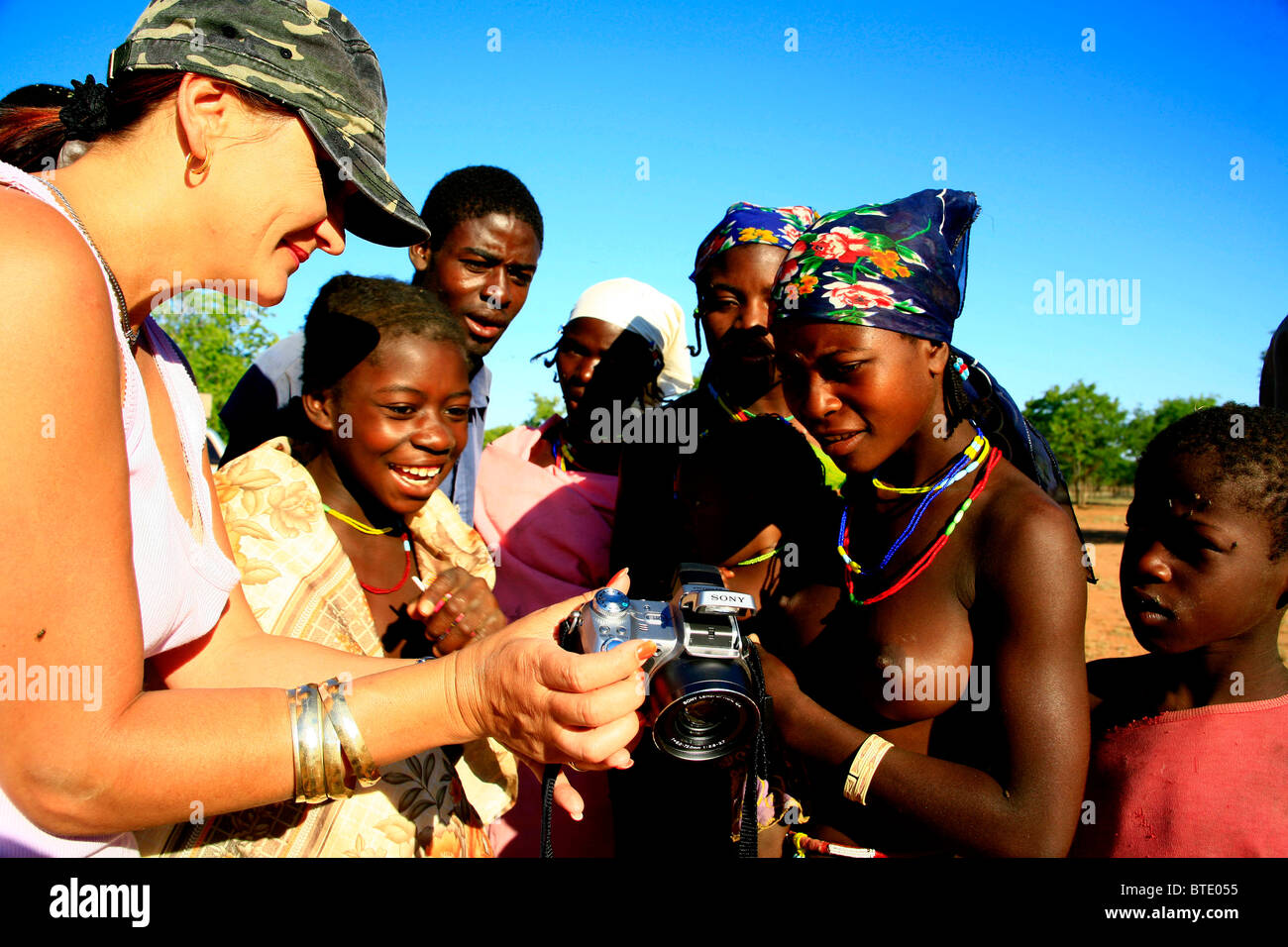 A group of local Angolan villagers look at pictures of themselves on a tourists digital camera Stock Photo