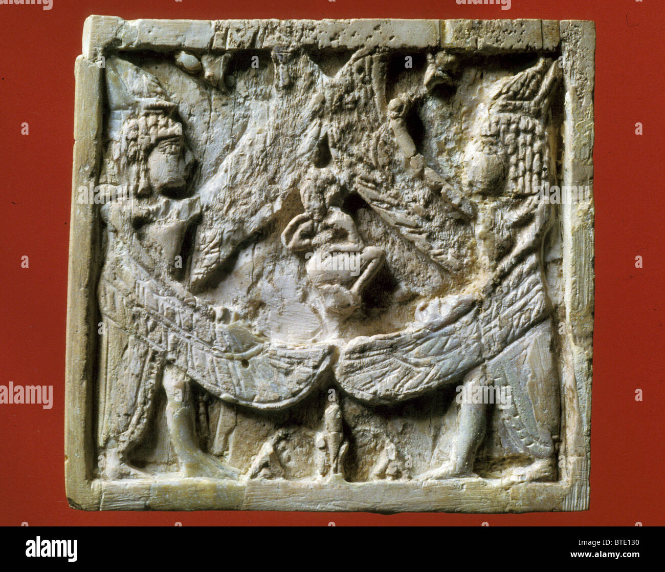 4B. IVORY PLATE DEPICTING TWO WINGED CREATURES SHELTERING A PERSON. SYRIA; ARSLAN TASH, 8TH. C. B.C. 'Above stood the Stock Photo