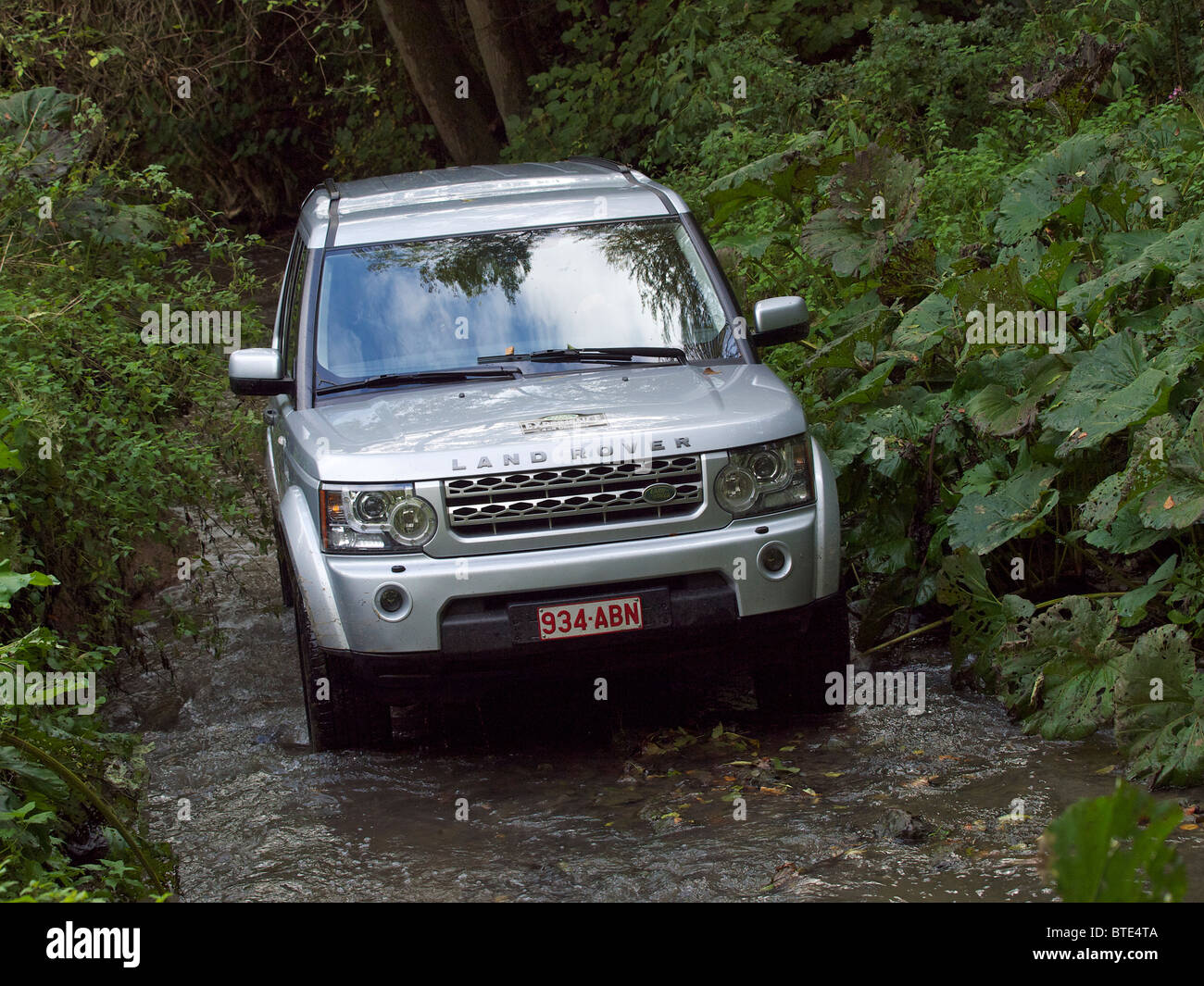 Silver Land Rover Discovery 4 driving through a creek at the Domaine d'Arthey estate in Belgium Stock Photo