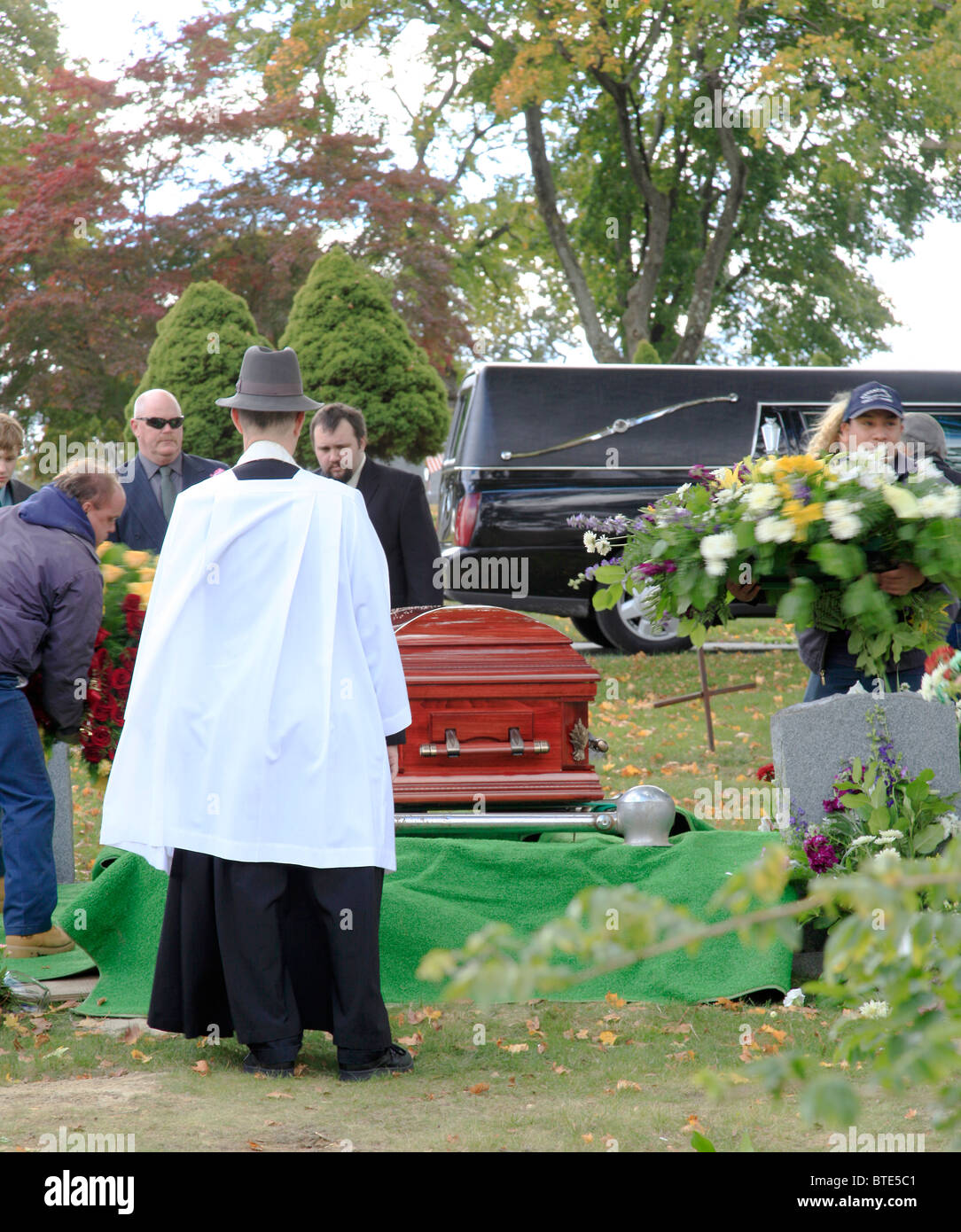 A funeral at a Catholic cemetery in New York,USA with a priest wearing