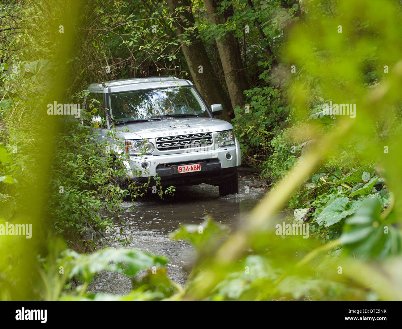 Silver Land Rover Discovery 4 driving through a creek at the Domaine d'Arthey estate in Belgium Stock Photo