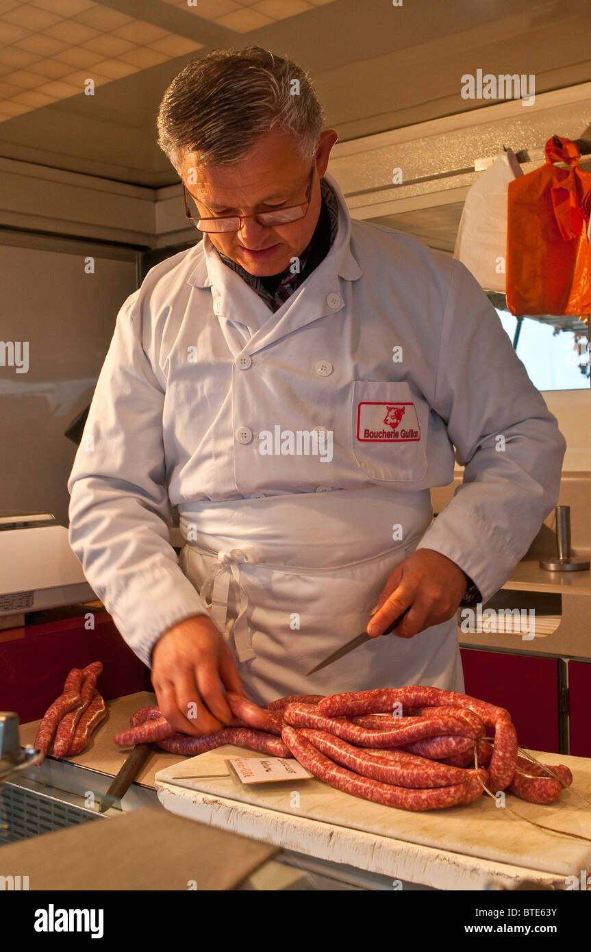 Butcher cutting pork sausages - France. Stock Photo