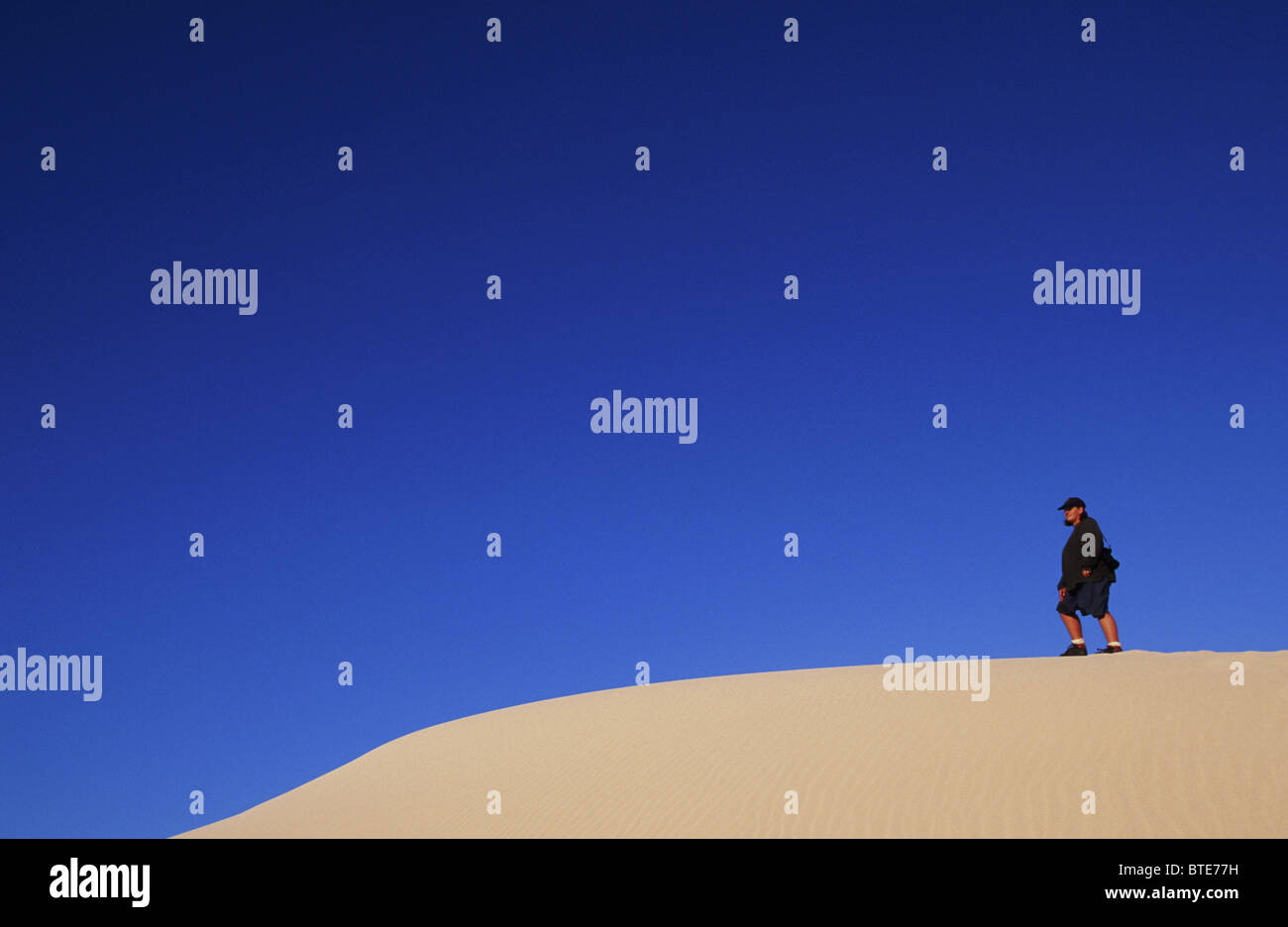A hiker walks along the ridge of a Dunes at the De Hoop Nature Reserve Stock Photo