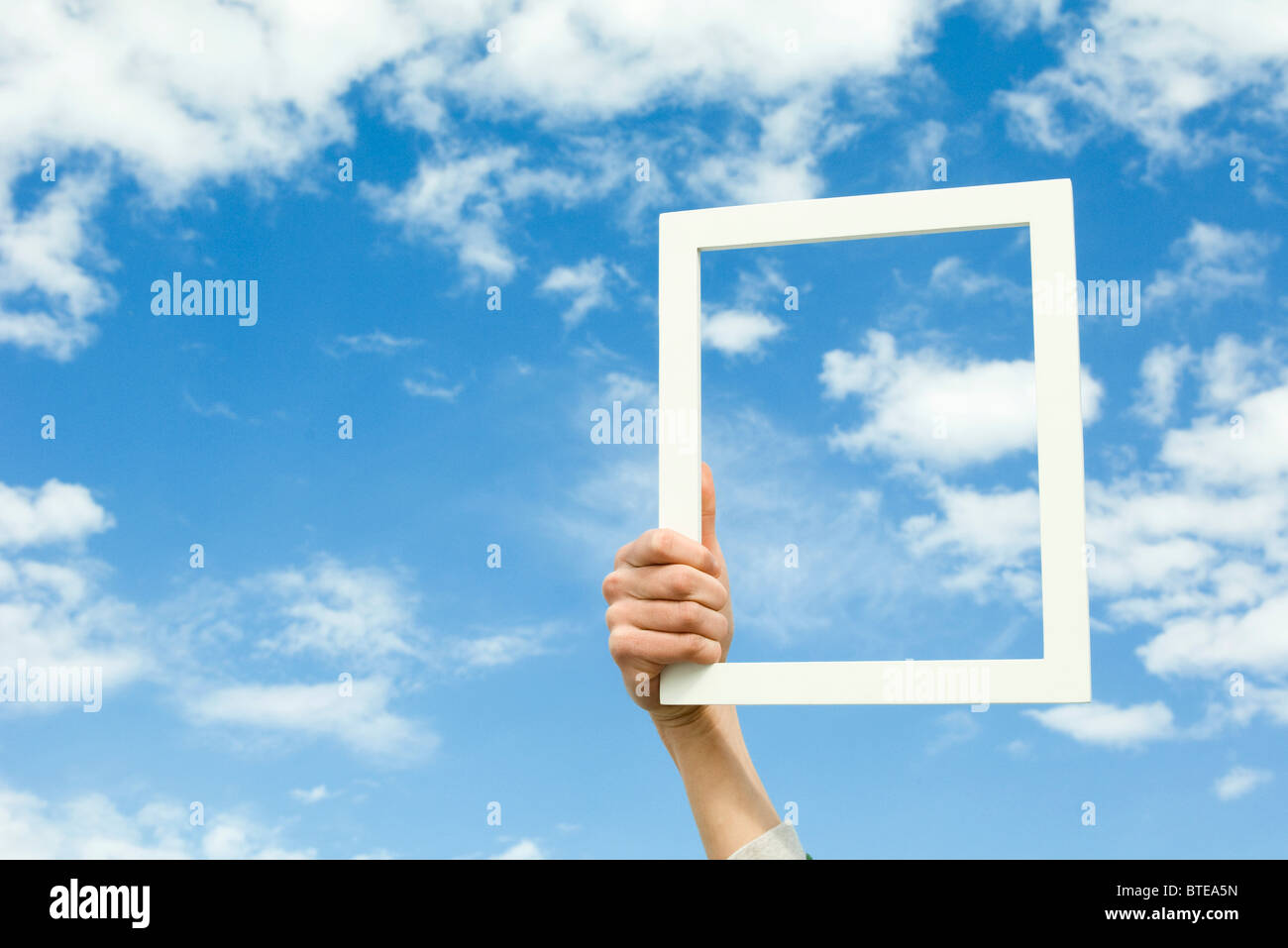 Person holding picture frame in front of sky Stock Photo