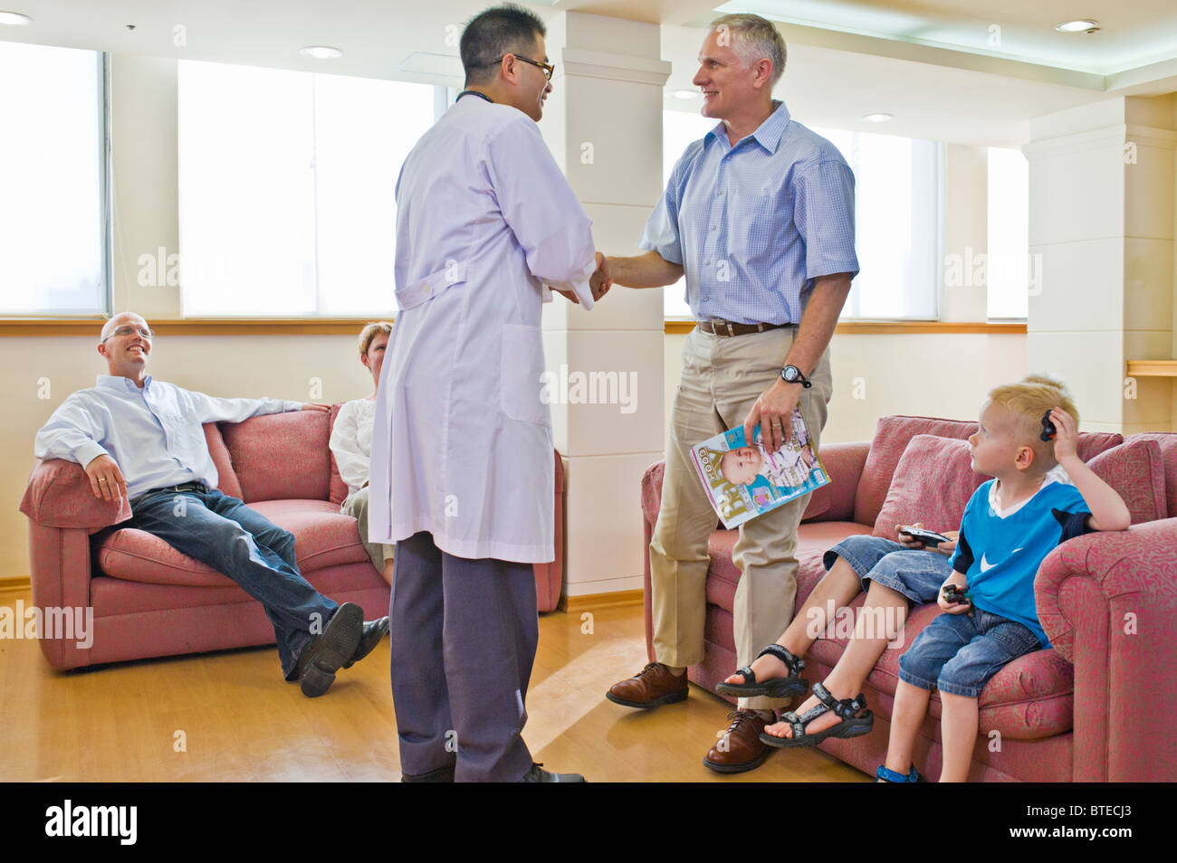 Doctor greeting patient in hospital waiting room Stock Photo