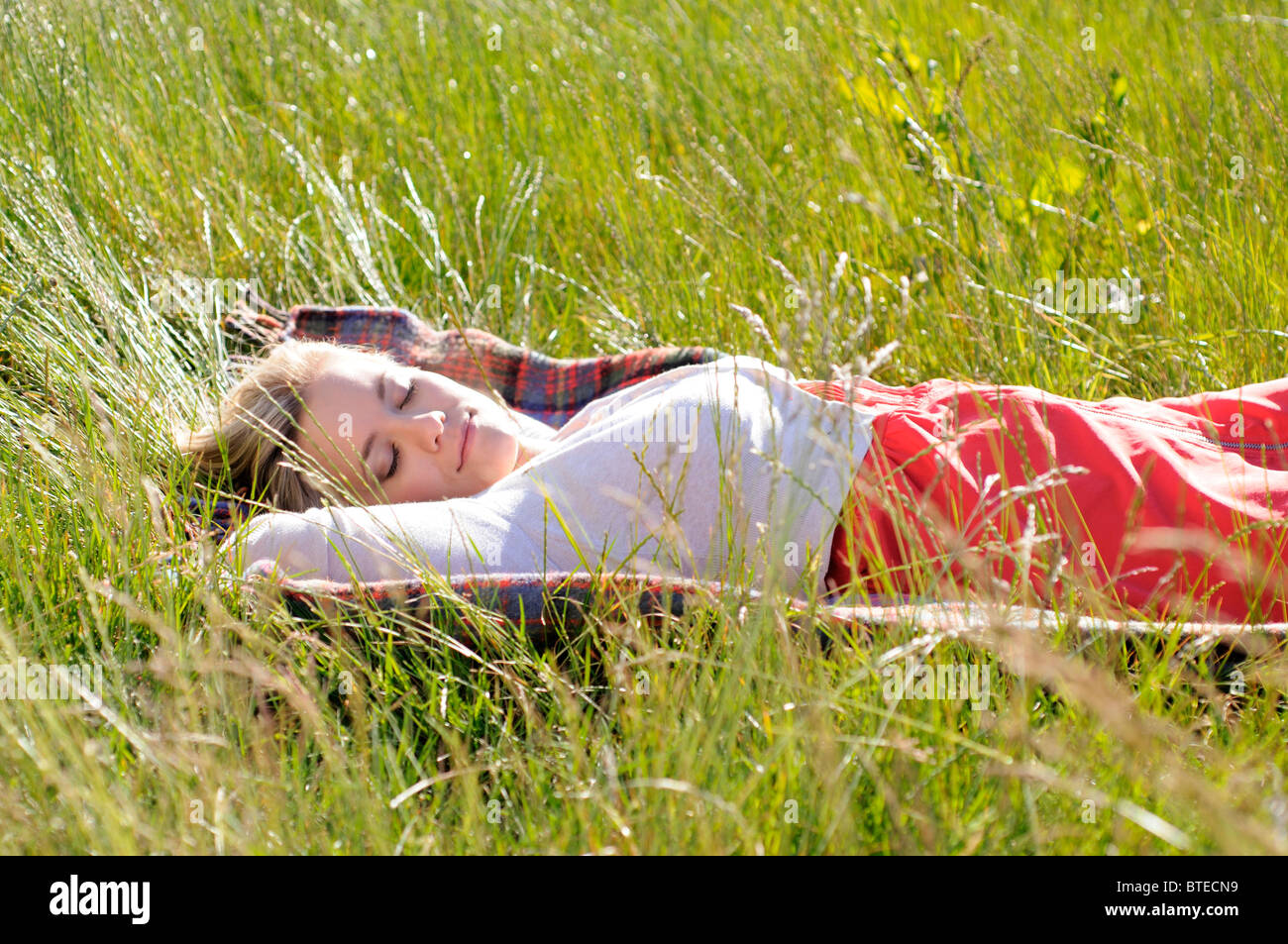 Young woman napping on blanket in tall grass Stock Photo Alamy