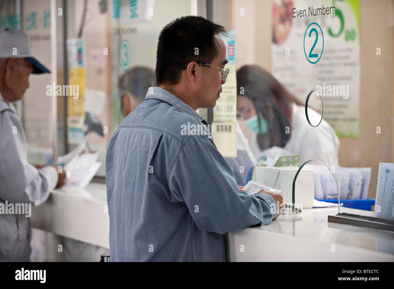 Man waiting to receive medicine at hospital pharmacy window, Taiwan Stock Photo