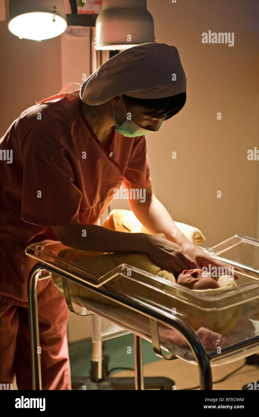 Nurse covering newborn baby with blanket Stock Photo