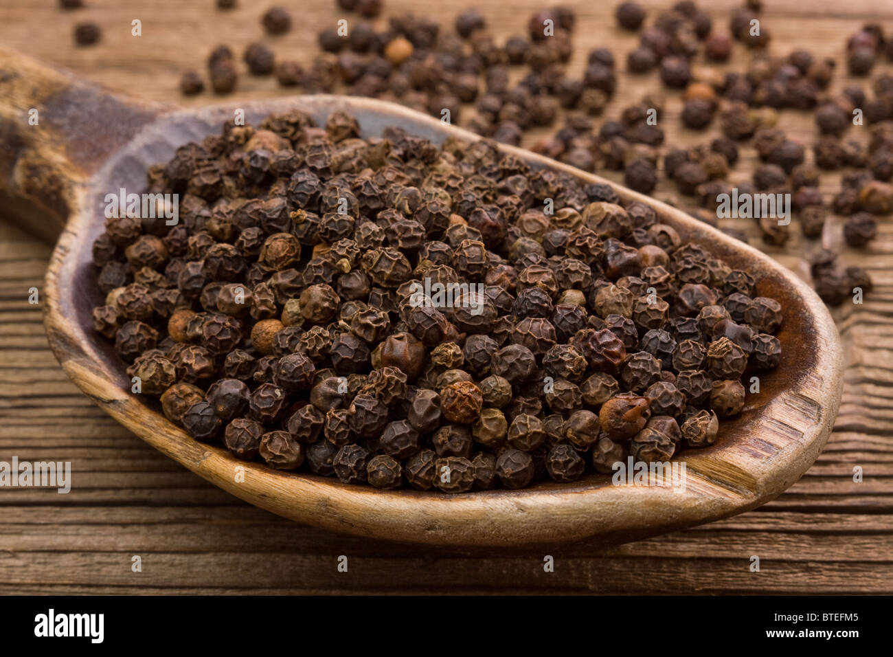 Black pepper and very old wooden spoon Stock Photo